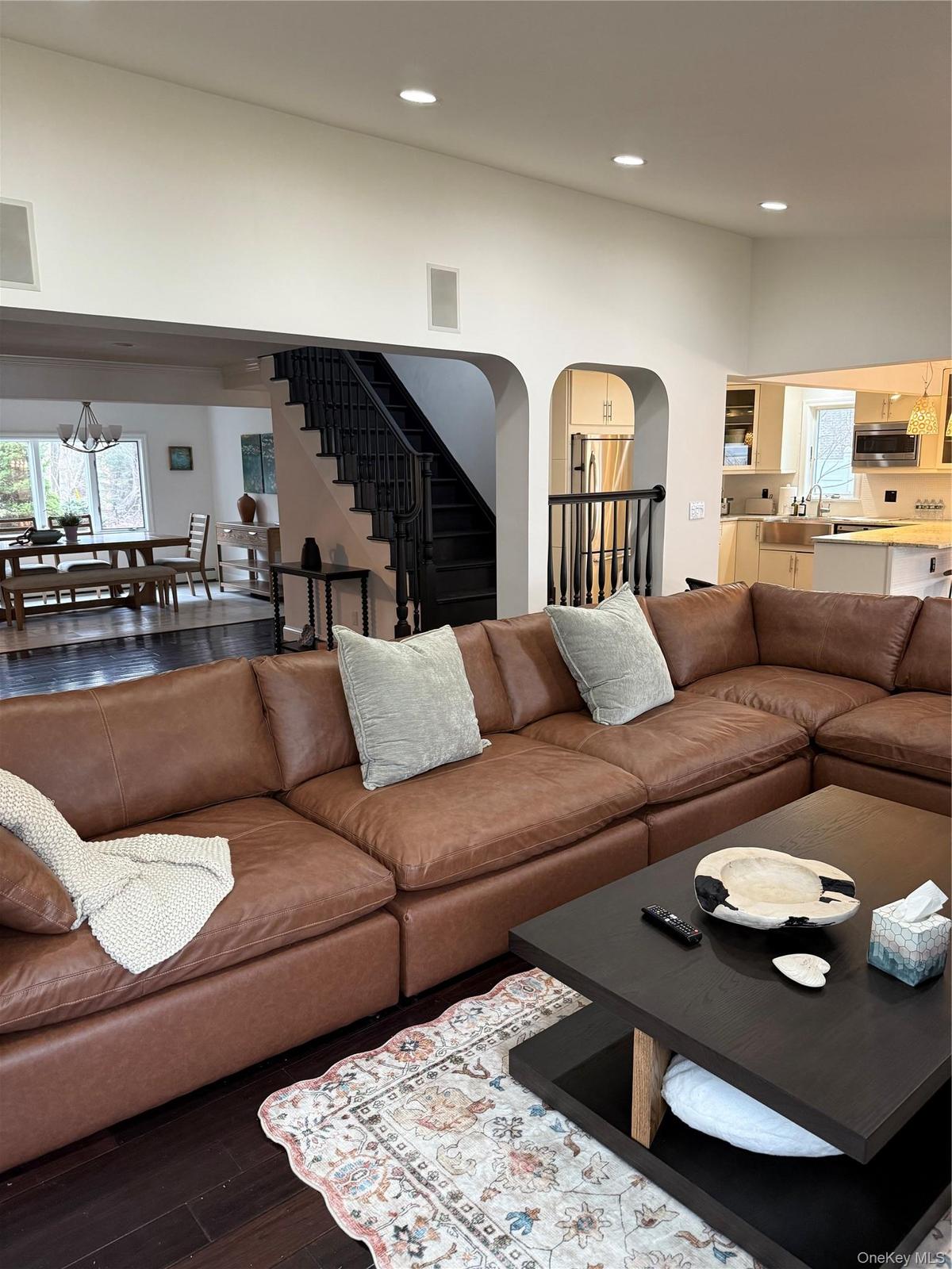 Living room featuring wood finished floors, plenty of natural light, recessed lighting, arched walkways, and stairs