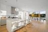 Kitchen featuring sink, tasteful backsplash, pendant lighting, a center island with sink, and light wood-type flooring