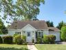 View of front of house with an attached garage, roof with shingles, a front yard, and driveway