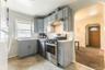 Kitchen with gray cabinets, appliances with stainless steel finishes, arched walkways, light countertops, and tasteful backsplash