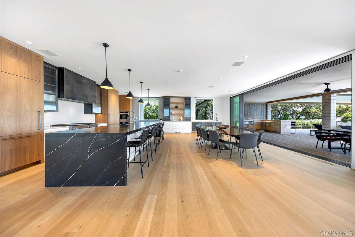 Kitchen featuring modern cabinets, a breakfast bar, healthy amount of natural light, a large island, and a wall of windows