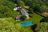 Aerial view of property and surrounding area featuring a pool and a heavily wooded area