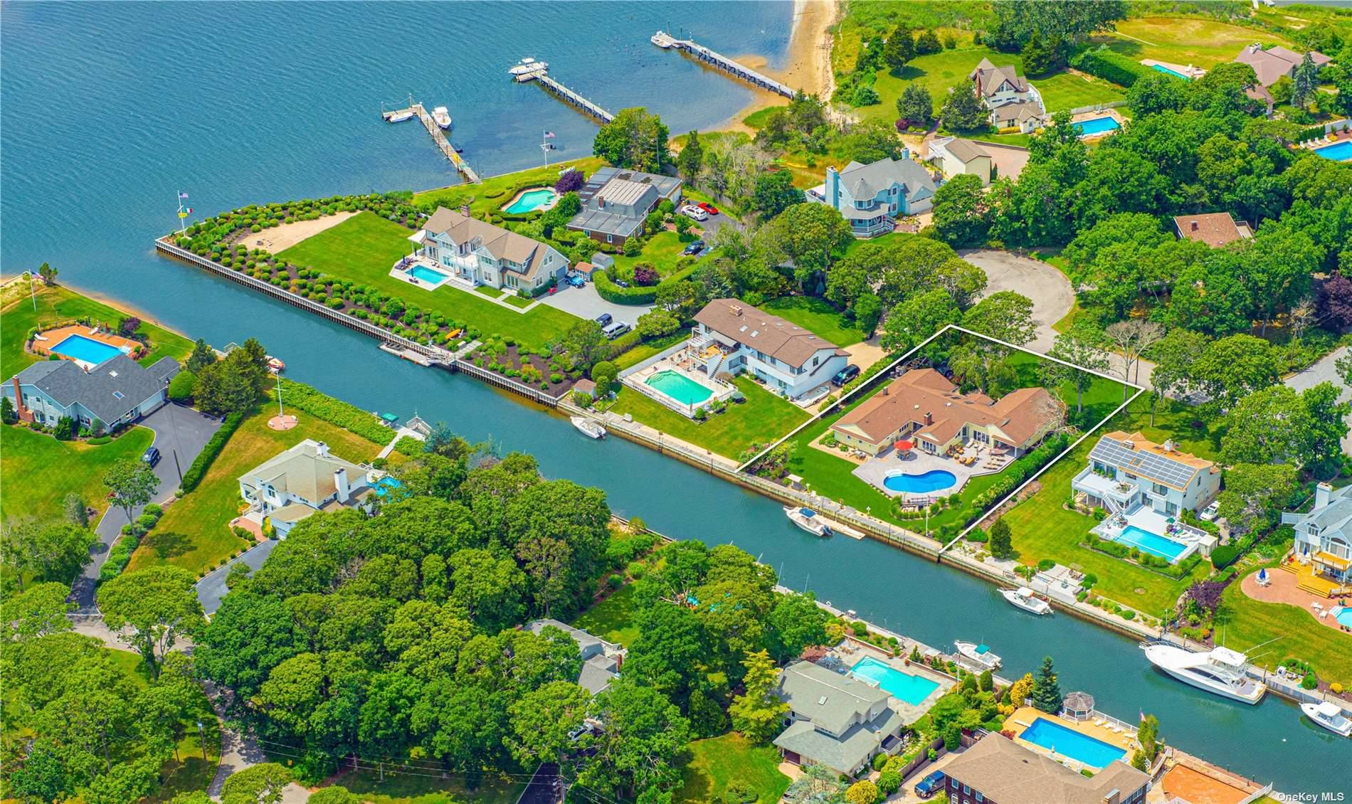 Located within the exclusive Old Harbor Colony Community in Hampton Bays, this stunning waterfront property offers a picturesque escape with luxurious amenities.