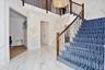 Stairway featuring a towering ceiling, marble tiled floors, a chandelier, and stone wall