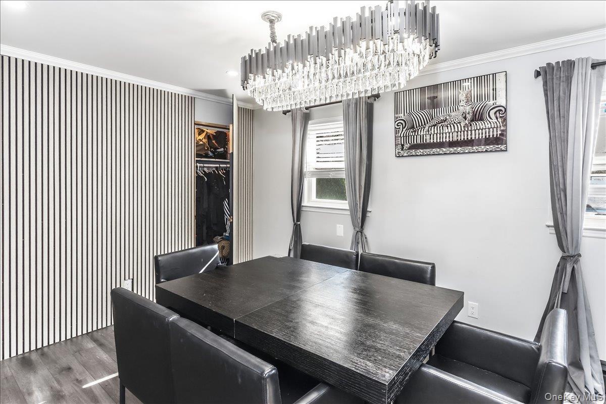 Dining area featuring a contemporary chandelier, wood-finish flooring, two windows, and a built-in closet with slatted panel doors