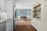 Kitchen with tasteful backsplash, white cabinetry, light stone countertops, and crown molding
