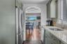 Kitchen featuring appliances with stainless steel finishes, light stone countertops, backsplash, green cabinets, and dark wood-type flooring