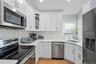 Kitchen with appliances with stainless steel finishes, white cabinetry, backsplash, glass insert cabinets, and recessed lighting