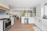 Kitchen with stainless steel gas stove, open shelves, open floor plan, wine cooler, and white cabinetry