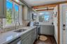 Kitchen with appliances with stainless steel finishes, gray cabinetry, dark wood finished floors, tasteful backsplash, and beam ceiling