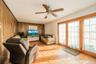 Living area featuring wood-finish flooring, wood paneling, and a ceiling fan