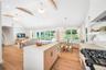 Kitchen featuring a chandelier, beam ceiling, black gas range, open floor plan, and light brown cabinets