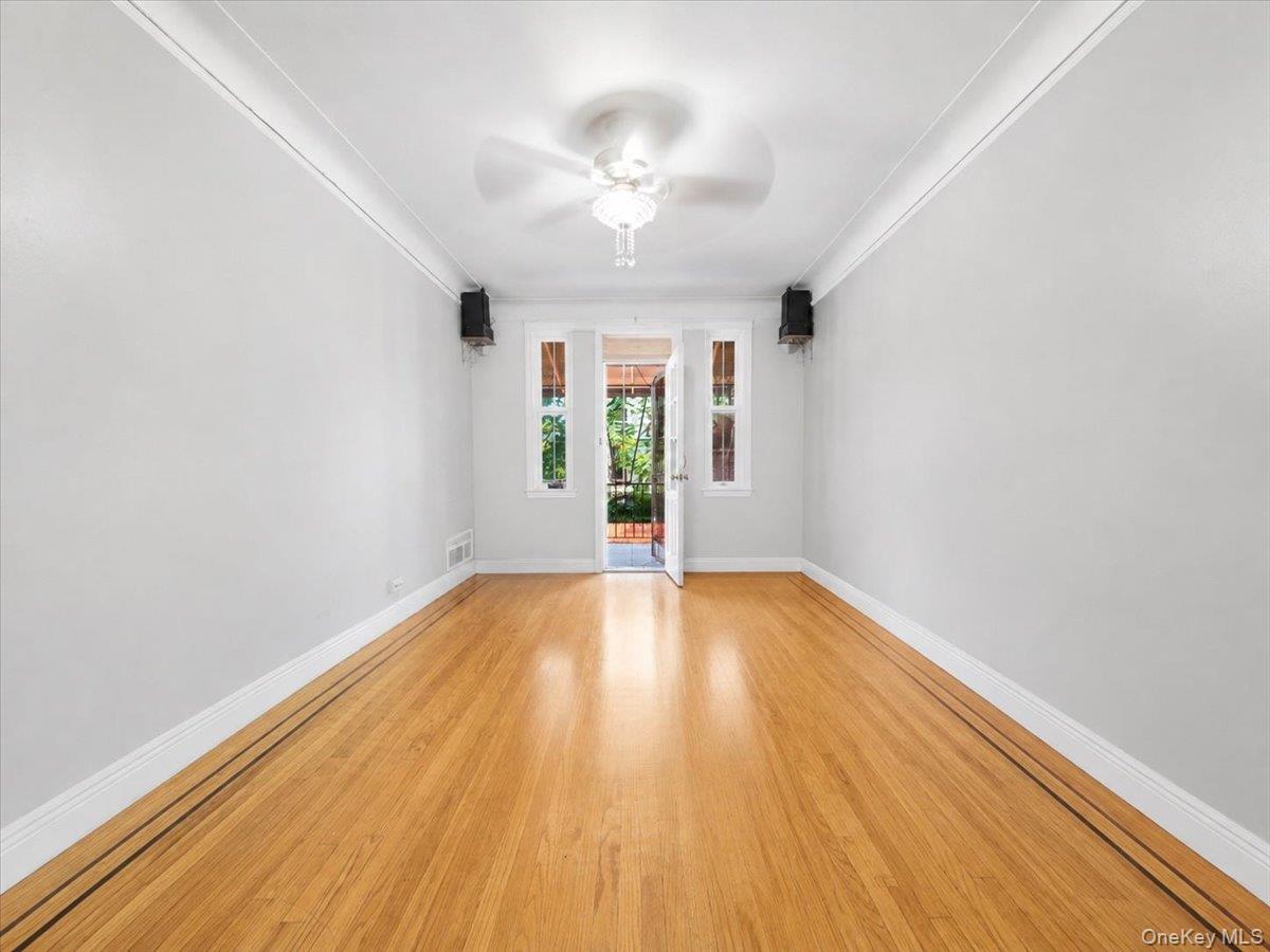 Hardwood flooring with decorative inlay, ceiling fan with light fixture, and crown molding