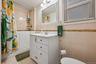 Full bath with tile walls, vanity, shower / bath combo, and light tile patterned floors