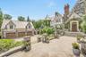 Stunning Tudor-style estate featuring stone and half-timber architecture, an ivy-covered turret, and a spacious motor court with a three car garage. T