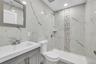 Bathroom with tile walls, vanity, a marble finish shower, and stone wall