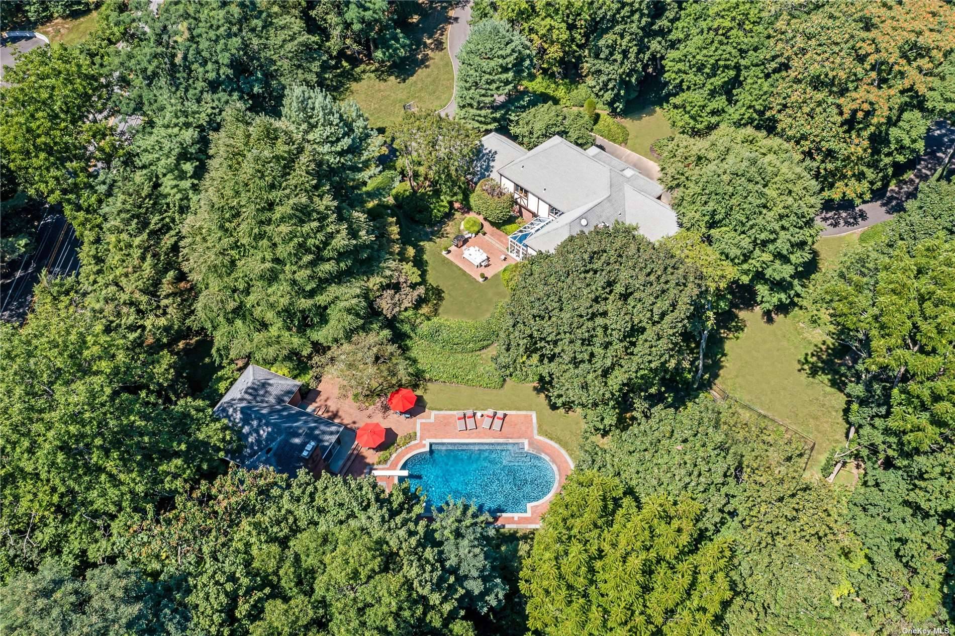 2 Sousa Drive is a brick and stucco Tudor Colonial and Cottage house situated on 2 pristine acres in the sought after Village of Sands Point.