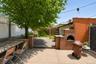 Spacious outdoor area featuring a built-in brick oven, concrete patio, and mature tree with string lighting
