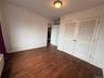 Unfurnished bedroom featuring dark wood finished floors, a closet, and a wall mounted air conditioner