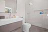 Bathroom with decorative backsplash, a tile shower, vanity, tile walls, and toilet