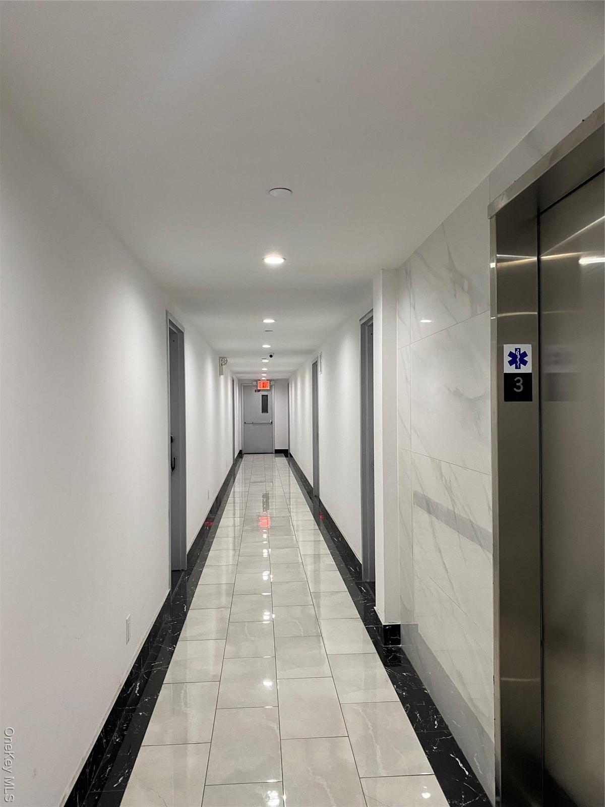 Hall featuring elevator, light marble finish flooring, inlaid floor details, and recessed lighting