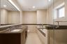 Bathroom featuring a dual vanity with integrated sinks, a built-in soaking tub, and a separate glass-enclosed shower