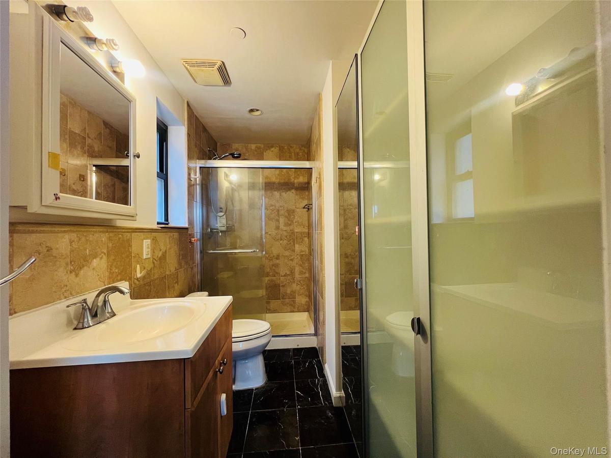 Full bath with vanity, a stall shower, and tile walls