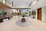 Expansive foyer with wide-plank light wood floors, walnut wall paneling, sculptural console with freeform mirror, marble round entry table, open secon