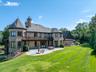 Back of house with a patio area, a chimney, brick siding, a balcony, and an outdoor fire pit