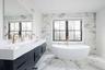 Bathroom with a soaking tub, double vanity, marble finish floors, and tile walls