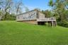 Back of property featuring stairway, a wooden deck, and a yard