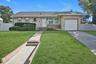 Ranch-style home featuring an attached garage, stucco siding, driveway, and roof with shingles