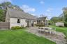 Rear view of house featuring a patio area, a sunroom, a fenced backyard, roof with shingles, and a storage shed
