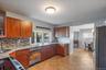 Kitchen featuring stainless steel appliances, glass fronted cabinets, light stone counters, and decorative backsplash
