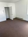 Carpeted spare room featuring a baseboard radiator