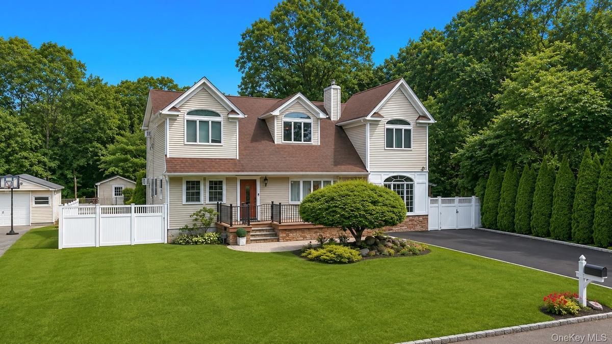 Two-story residence featuring light-toned siding, a brown shingle roof, and multiple dormer windows