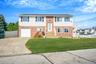 Raised ranch featuring driveway, brick siding, and a garage