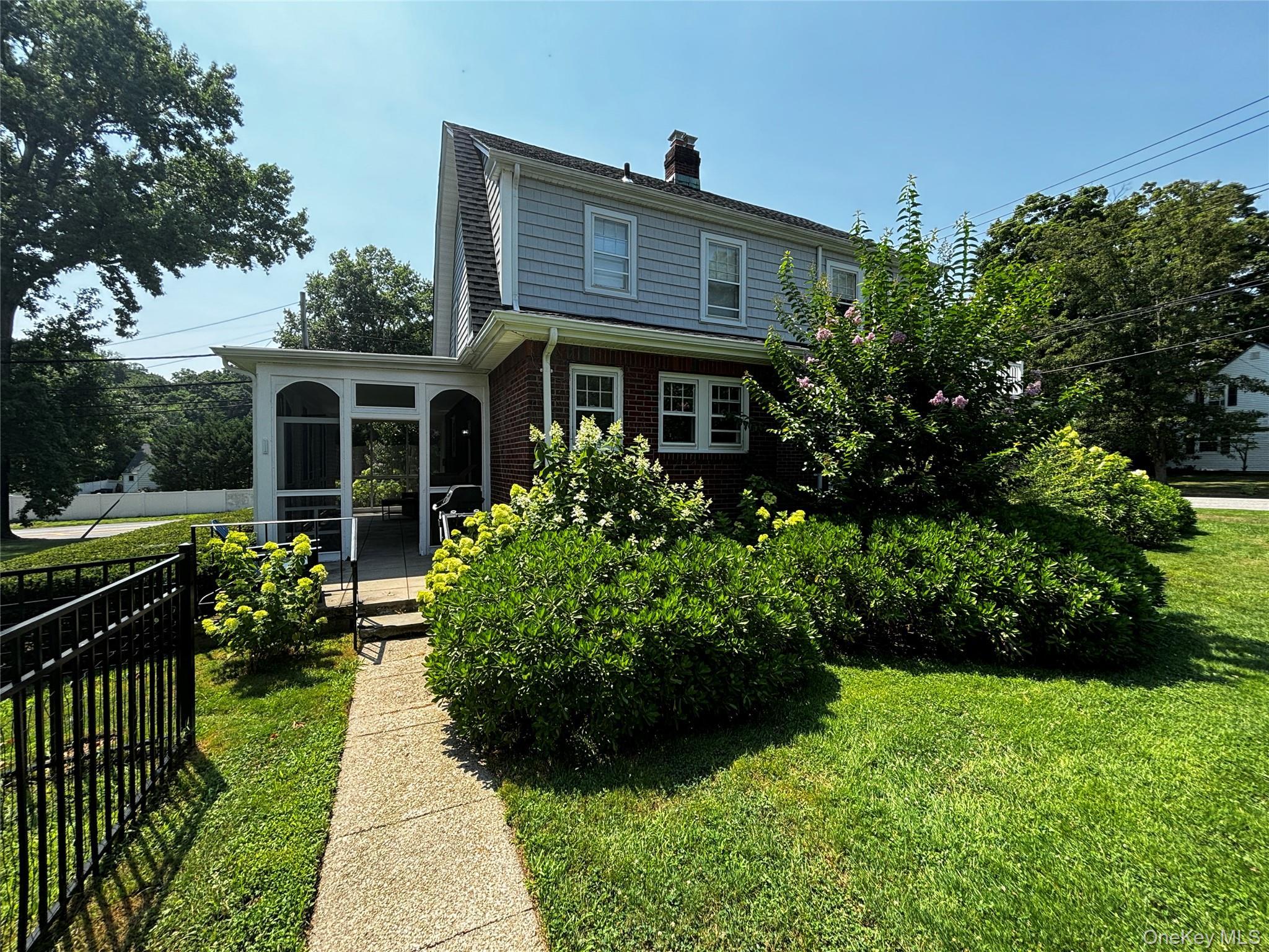 Rear view of house featuring a chimney, brick siding, a sunroom, a yard, and fence