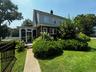 Rear view of house featuring a chimney, brick siding, a sunroom, a yard, and fence
