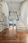 Staircase featuring wood finished floors, a chandelier, and a towering ceiling