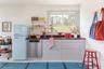 Kitchen with stainless steel dishwasher, freestanding refrigerator, white cabinets, and butcher block countertops