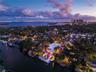 High-altitude aerial at twilight showing full property footprint, private dock, deep-water canal, pool, manicured grounds, and expansive panoramic vie