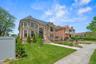 View of front facade featuring a high end roof, stone siding, and brick siding