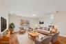 Spacious living area featuring wood-finish flooring, light neutral walls, and a large sliding glass door with a balcony