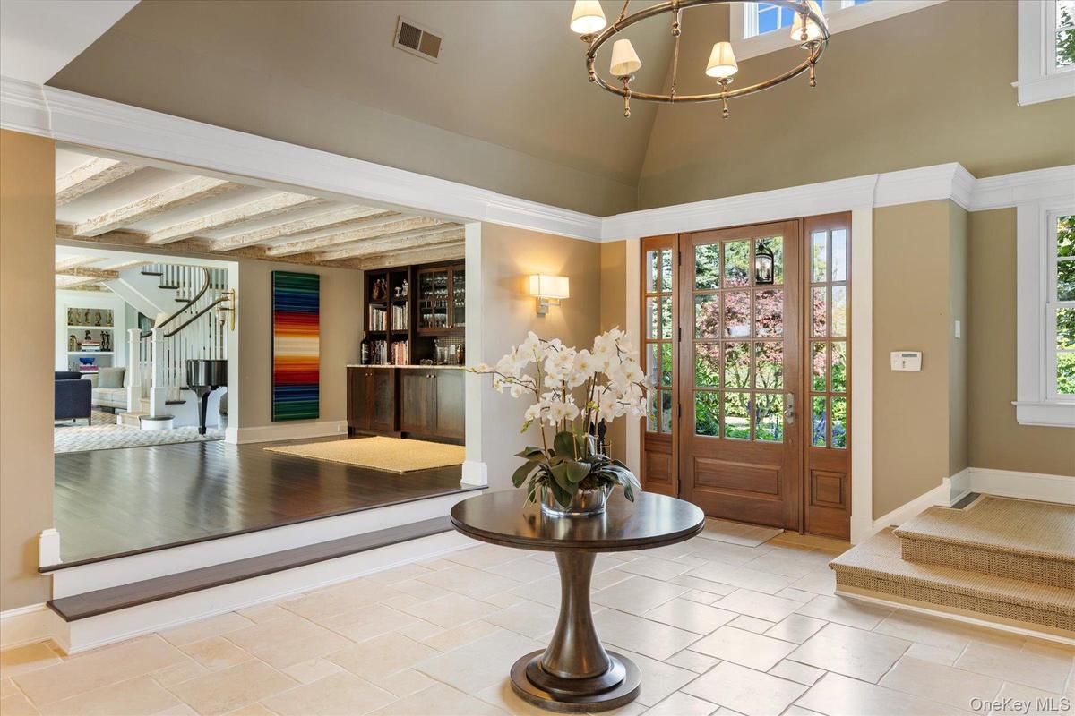 Entrance foyer featuring stairs, beamed ceiling, and a chandelier