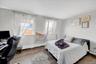 Room featuring two windows with sheer curtains, light gray walls, and wood-finish flooring