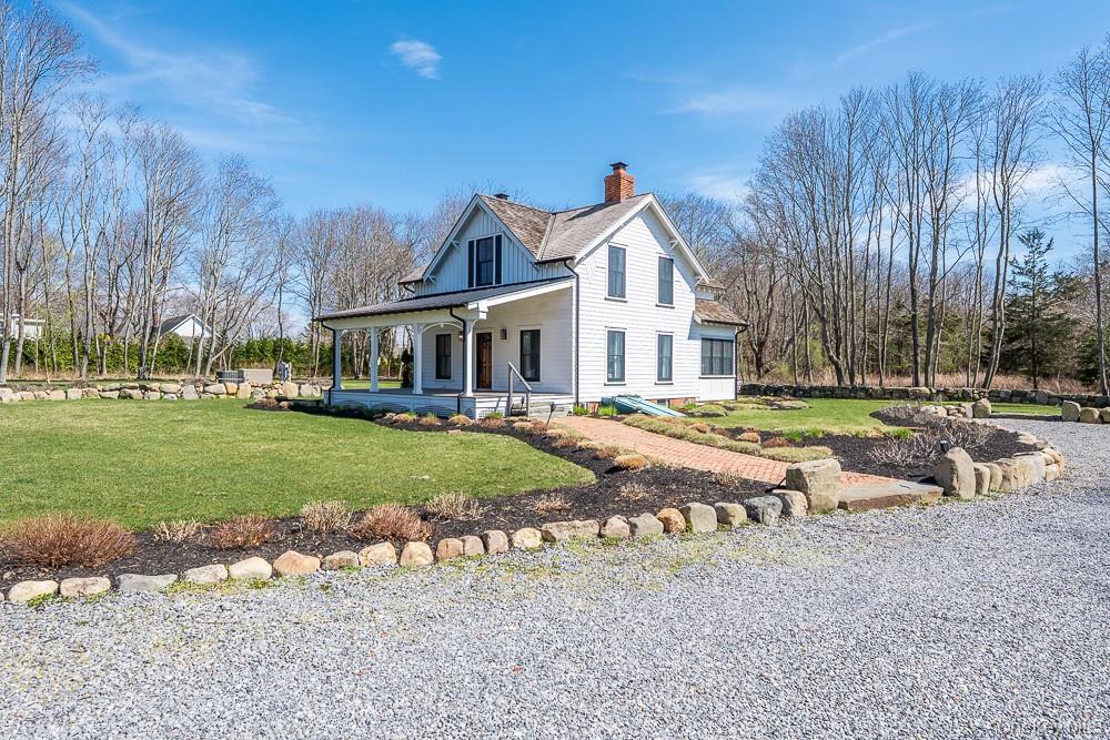 View of home's exterior featuring a chimney, covered porch, a lawn, and a shingled roof
