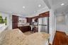 Kitchen featuring a wainscoted wall, stainless steel appliances, light stone counters, backsplash, and ornamental molding
