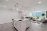 From the kitchen, enjoy an open-concept view that seamlessly connects the dining and living areas. Sleek tile flooring and designer lighting create a