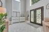 Double iron entry doors featuring crushed glass panels, stacked stone accent wall, over-sized elliptical windows providing a warm ambiance of light, e